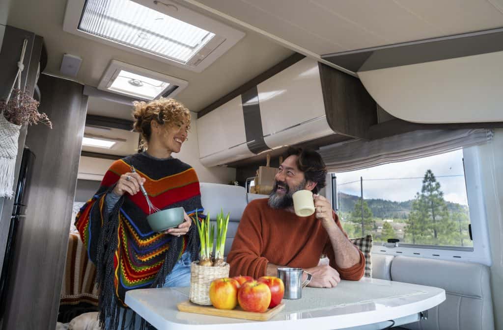 A couple inside of their RV eating breakfast and drinking coffee